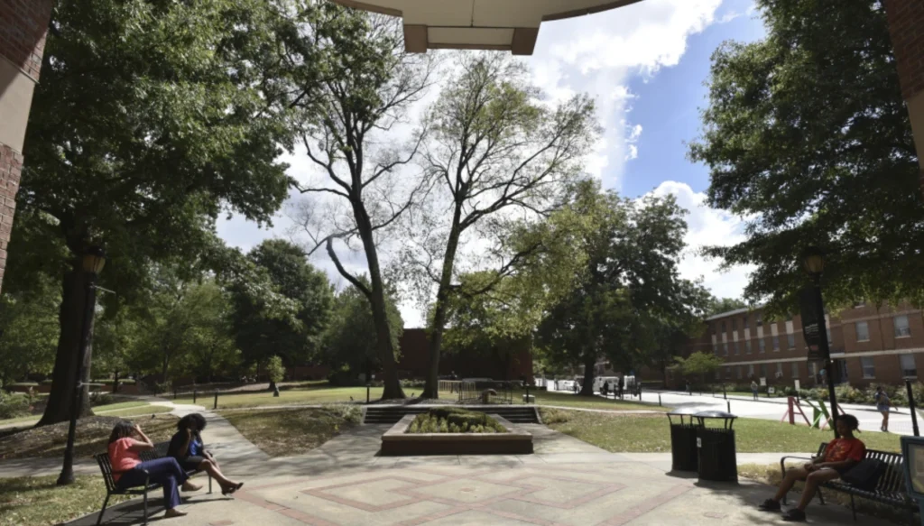 HBCU campus courtyard with students relaxing on benches under trees